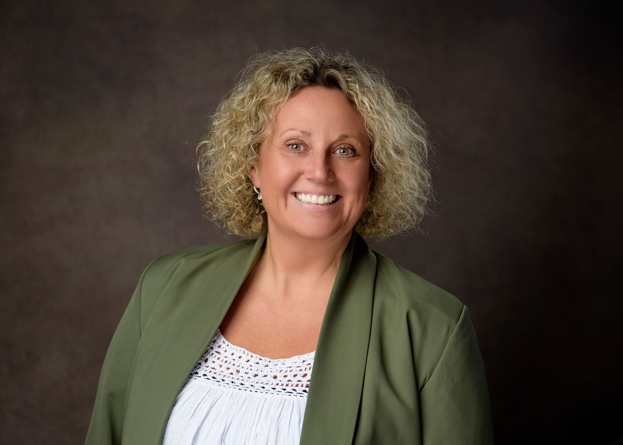 Anna Bates smiling in a green blazer.