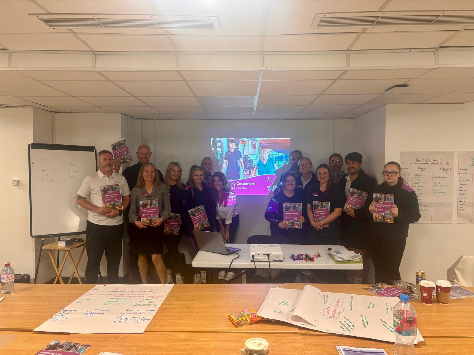 Workshop participants holding their Delighting Customers training workbooks.