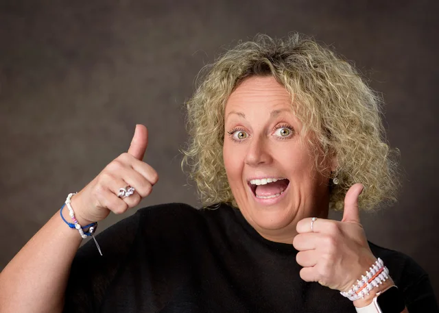 Anna Bates enthusiastically giving two thumbs up in a black top.